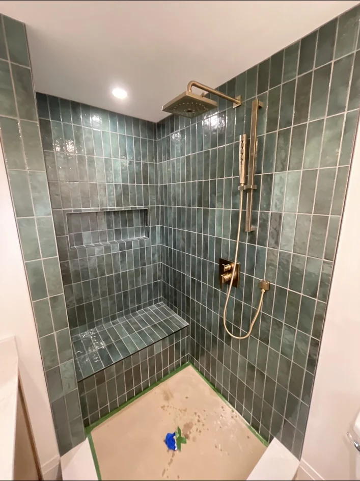 Finished green tiled shower with brass fixtures