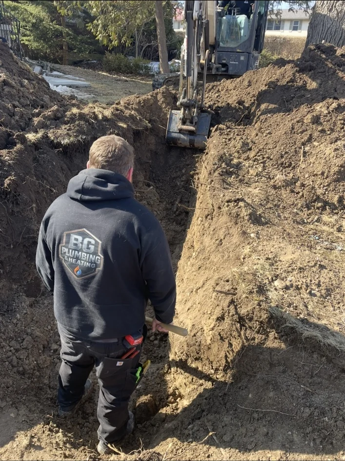 BG Plumbing technician working in an excavated trench